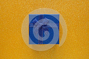 Blue gift box on glitter yellow background with copy space. Top view. Xmas, Valentines day or birthday party concept. Greeting