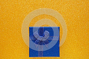Blue gift box on glitter yellow background with copy space. Top view. Xmas, Valentines day or birthday party concept. Greeting
