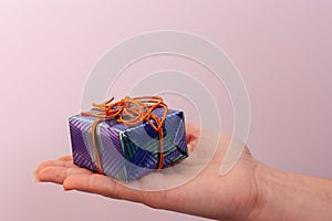 A blue gift box lies on an open female palm.