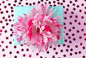 Blue gift box with pink ribbon bow on pink background with confetti. Flat lay.