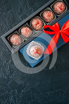 Blue gift box with red tape and chocolate on a black stone background