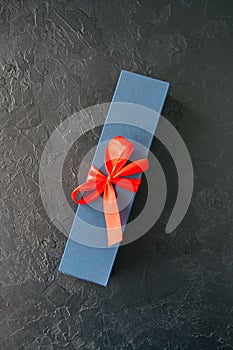 Blue gift box with red tape and chocolate on a black stone background