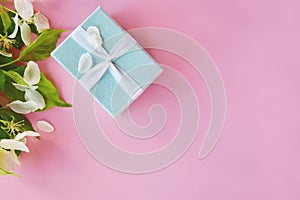 Blue gift with flowers of an apple tree on a pink background. Beautiful background top view, copy space. love message,