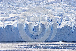 Blue glacier face in silhouette with big crevices