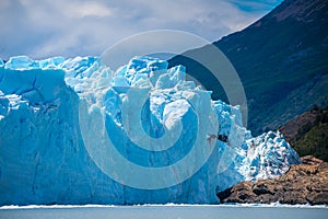 The blue glacier stands on the water and on the shore. Shevelev.