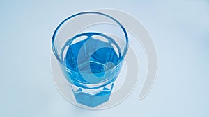 Blue glass with fresh purified drinking water on a light background.