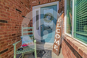 Blue glass paned front door with wreath and sidelight against brick wall of home