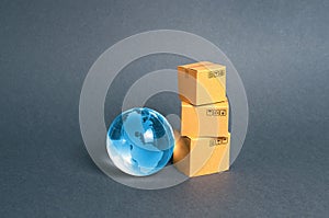 Blue glass planet globe and a stack of cardboard boxes. The concept of commerce and trade, cargo delivery, exchange of goods