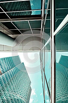 blue glass wall of skyscraper. Looking up of sky reflections on part of glass buildings