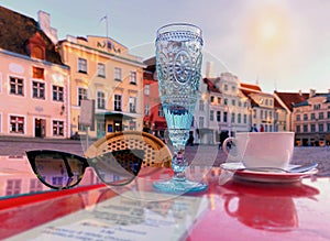 Blue glass of wine ,white cup of coffee and sunglasses on red table top in street cafe  ,blue sky,sunny day in the medieval city ,