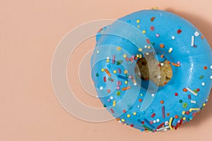 Blue glazed donut with sprinkles on pink background.