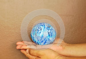 Blue globe on both hands, background, brown wall, light, support the world, cared world, push the world, the world environment,