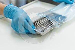 A blue-gloved dentist pulls out a tray of dental instruments.