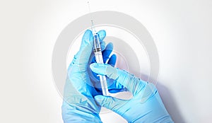 A blue-gloved hand holds a syringe on the white background