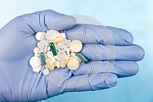 Blue-gloved hand pulls a handful of pills