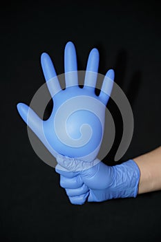 Blue gloved hand, raised thumbs up, closed point, on black background