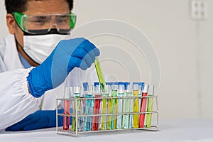 Blue gloved scientist hands holding a bottle with laboratory glassware in a doctor`s science lab research and development concept.