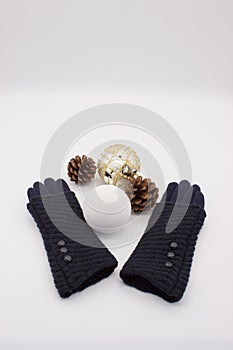 Blue gloves, white and golden Christmas balls and two pine cones on a white background. New YearÃ¢â¬â¢s and Christmas Concept