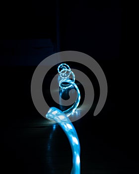 Blue glowing LED strip with cold light on a black background close-up, decorative lighting