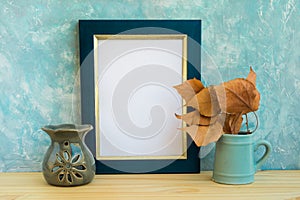 Blue and golden frame mockup, concrete wall background, wood table, fry leaves, aroma therapy lamp, autumn, fall, tranquility