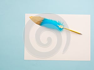 Blue and golden quill pen ron white paper isolated on light blue