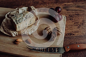 Blue grapes and cheese on dark wooden background.