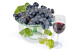 Blue grapes on vintage fruit vase, vine twig, red wine