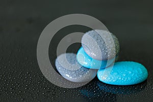 Blue and gray pebbles with drops of water arranged in zen lifestyle on black background