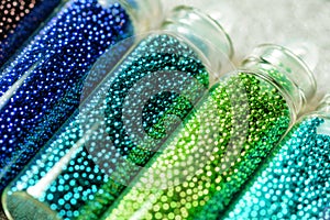 Blue and green beads in bottles for nail design close-up