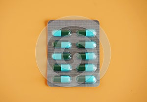 Blue-green capsule pill panel on orange background. Amoxicillin is a penicillin antibiotic. It is used to treat infections caused