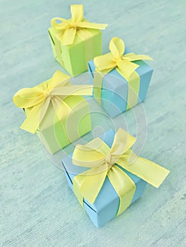 Blue and green, four square gift boxes on blue-green watercolor textured background, vertical photo image.