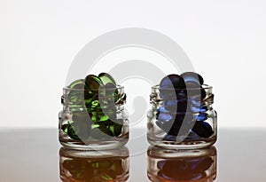 Blue and green pills in glass jars, granules