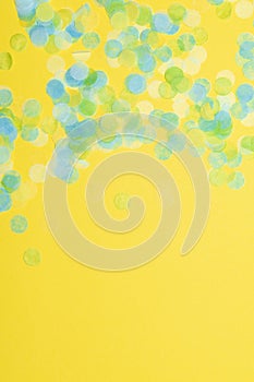 Blue green and yellow paper confetti on a vibrant yellow background