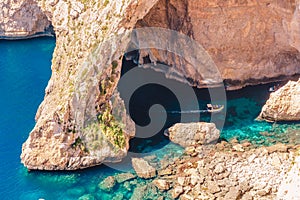 Blue Grotto in Malta. Pleasure boat with tourists runs. Natural arch window in rock