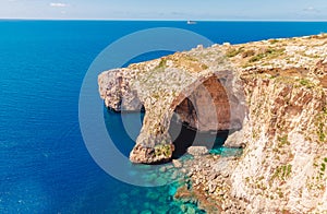 Blue Grotto in Malta. Pleasure boat with tourists runs. Natural arch window in rock