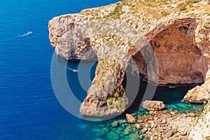 Blue Grotto in Malta. Pleasure boat with tourists runs. Natural arch window in rock