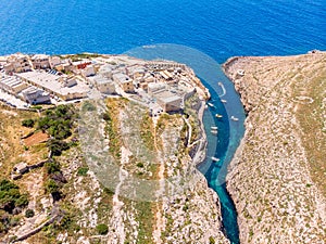 Blue Grotto in Malta. Pleasure boat with tourists runs. Natural arch window in rock. Aerial top view.