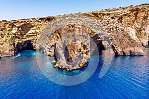 Blue Grotto in Malta. Pleasure boat with tourists runs. Natural arch window in the rock. Aerial top view.