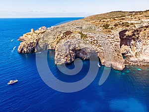 Blue Grotto in Malta. Pleasure boat with tourists runs. Natural arch window in rock. Aerial top view.