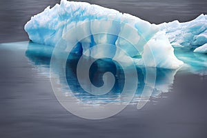 Blue growler (piece of iceberg) with reflection in calm water