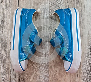 Blue gym shoes on a wooden background. View from above.