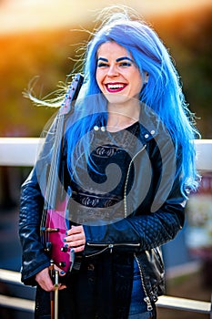 Blue hair woman buskers with violin outdoor in in sun shine. photo