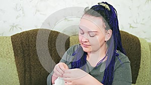 The blue-haired bride on the sofa sews her wedding dress by hand with a needle and thread