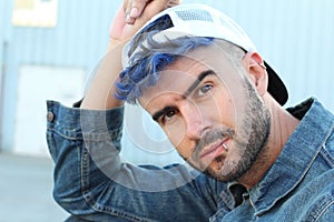 Blue haired pierced trendy male wearing a baseball cap