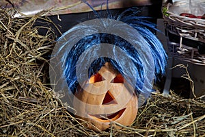 blue-haired pumpkin . Halloween pumpkin grinning in the most evil fashion . Spooky Halloween Jack o Lantern . Pumpkin on dry straw