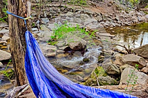 Blue hammock in the woods with a small river