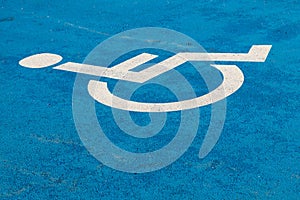 Blue handicap parking sign on asphalt for persons with disability