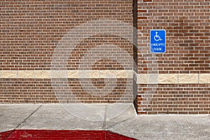 Blue handicapped parking sign on a red brick wall of an office building in the United Sates of America