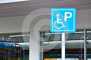 Blue handicapped sign mark parking spot, disabled parking permit sign on pole with convenience store in gas station