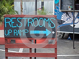 Blue handwritten restrooms up ramp sign on chalk board pointing right